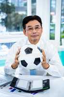 Asian businessman holding soccer ball