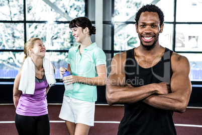 Smiling man with arms crossed while women chatting Smiling man with arms crossed while women chatting