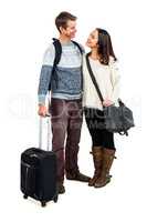 Full length of cheerful couple in warm clothing with luggag