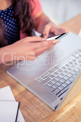 Businesswoman holding smartphone while sitting on