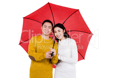 Portrait of happy young couple under umbrella