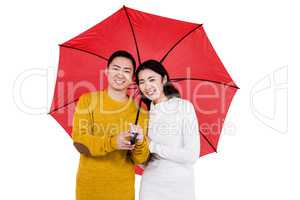 Portrait of happy young couple under umbrella