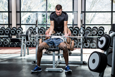 Trainer helping muscular man lifting barebell