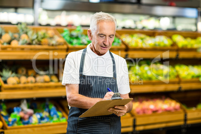 Mature worker writing on clipboard