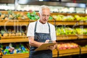 Mature worker writing on clipboard