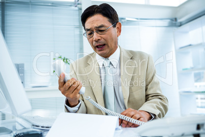 Frustrated businessman looks his phone