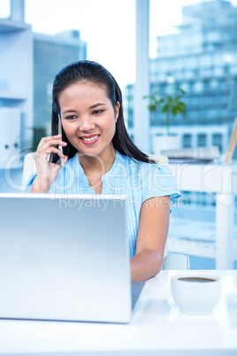 Smiling businesswoman on phone using laptop