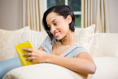 Smiling brunette reading book