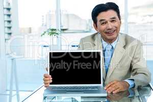 Smiling asian businessman showing laptop