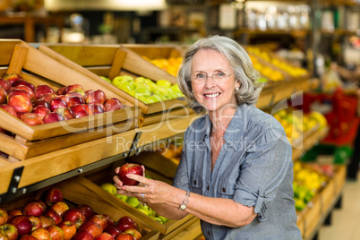 Smiling senior woman picking apple