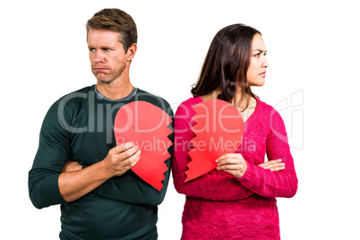 Serious couple holding cracked heart shape