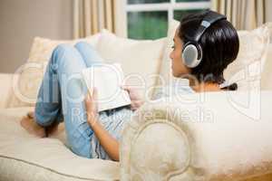 Brunette with headphones reading a book