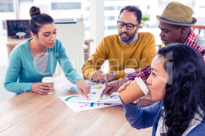 Businesswoman drinking coffee with colleagues in background