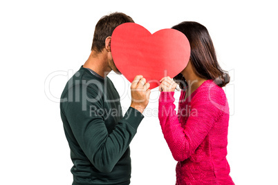Couple covering faces with heart shape
