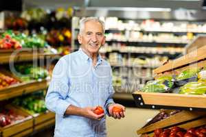 Smiling senior man picking out tomatoes
