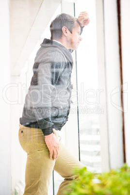 Thoughtful businessman leaning on glass window