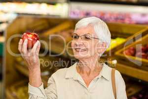 Senior woman holding and watching a red apple
