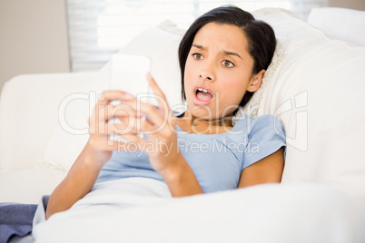 Surprised brunette using smartphone