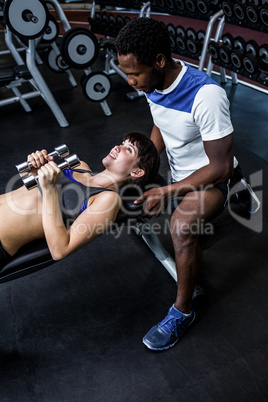 Male trainer assisting fit woman