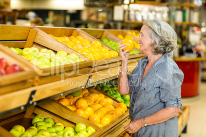Smiling senior woman smelling orange Smiling senior woman smelling orange