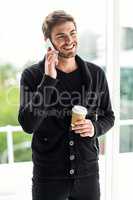 Handsome man on phone call holding disposable cup