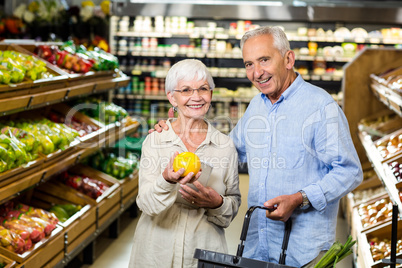 Smiling senior couple holding fruit