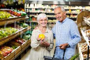 Smiling senior couple holding fruit