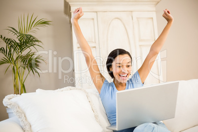 Happy woman using laptop and raising arms