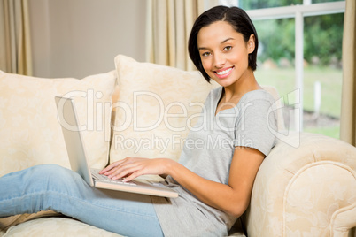 Smiling brunette using laptop