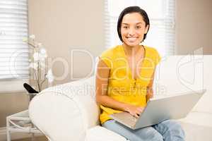 Smiling brunette using laptop