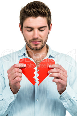 Sad man holding heart halves