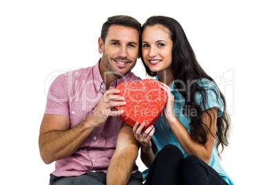 Portrait of smiling couple holding heart shaped box