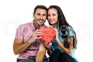 Portrait of smiling couple holding heart shaped box
