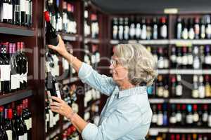 Smiling senior woman choosing wine