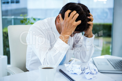 Worried businessman with head in hands