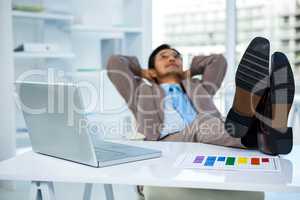 Successful businessman relaxing with his feet on his desk