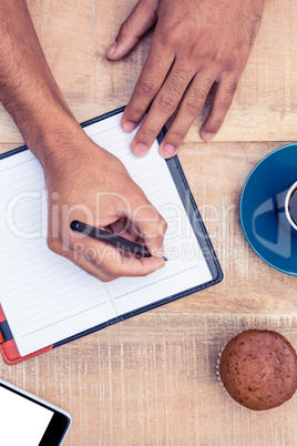 Person writing on diary at table