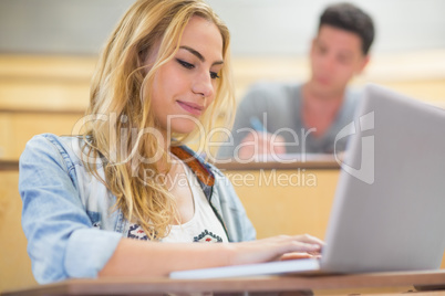 Smiling attractive student using laptop