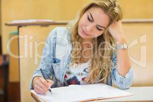 Thoughtful attractive student writing during class