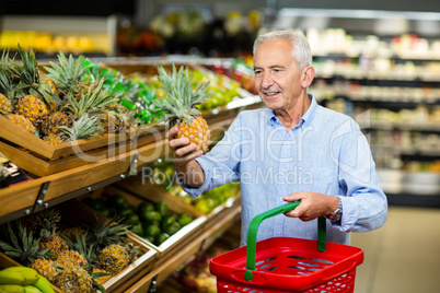 Smiling senior man picking pineapple