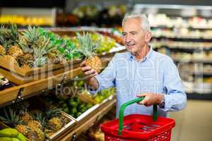 Smiling senior man picking pineapple