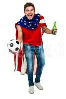 Handsome sport man rejoicing holding football ball and beer