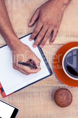 Overhead view of man writing on diary