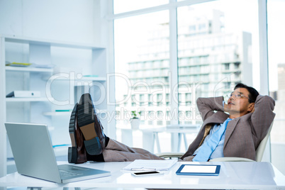 Businessman relaxing with his feet on his desk