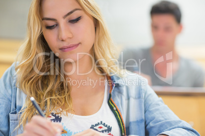 Serious female student writing during class