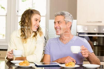 Happy couple using tablet and having breakfast