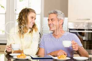 Happy couple using tablet and having breakfast