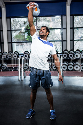 Smiling muscular man lifting kettlebells