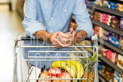 Senior man using phone at grocery store