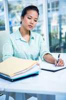 Smiling young businesswoman writing notes